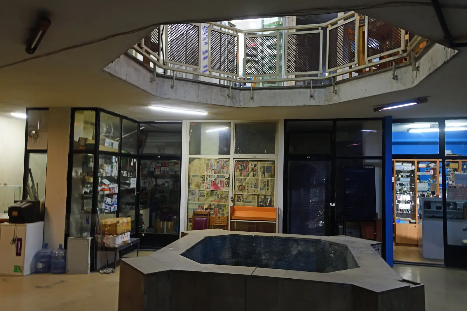 Kamenná kašna uprostřed sálu ve starém hamamu, s galerijním zábradlím a kupolí nad sebou